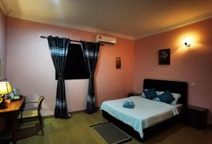 a bedroom with a bed and a desk and a window at Matamban motel in Kudat
