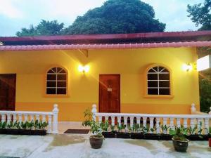 a yellow house with a white fence in front of it at Matamban motel in Kudat