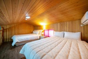 a bedroom with two beds in a wooden room at Reedforest Pension Suncheon in Suncheon