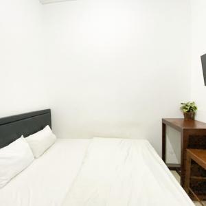 a bedroom with a white bed and a table at Village Homestay Yogyakarta RedPartner in Yogyakarta