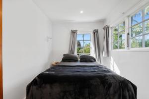 Ce lit se trouve dans un dortoir blanc doté de 2 fenêtres. dans l'établissement Okere Retreat - Lake Rotoiti Getaway, à Okere Falls