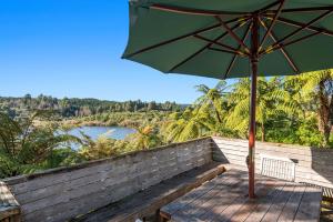 un parapluie vert posé sur un banc en bois à côté d'une rivière dans l'établissement Okere Retreat - Lake Rotoiti Getaway, à Okere Falls