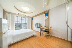 a bedroom with a bed and a table and a clock at Gangneung Windmill Pension Pet friendly in Gangneung