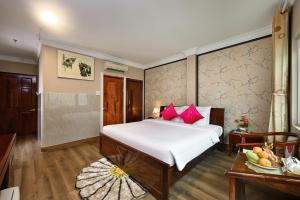 una camera da letto con un letto con cuscini rossi e un tavolo di Pink Boutique Ben Thanh Hotel ad Ho Chi Minh