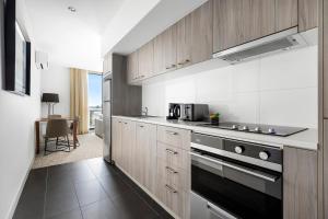 a kitchen with wooden cabinets and a stove top oven at Quest Chatswood in Sydney