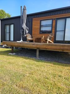 a bench with chairs and an umbrella in front of a cabin at Milfarrago Farm Stay in Farnborough