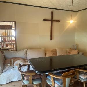 a dog laying on a couch in a living room with a cross at 民泊 inori in Dekiji