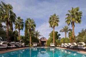 - une piscine avec des chaises longues et des palmiers dans l'établissement Palais de l'O, à Marrakech