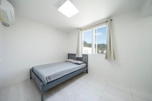 a white bedroom with a bed and a window at Yangyang Jangyo House Dog Pool Villa Pension in Yangyang +7 photos