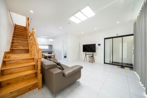 a living room with a couch and a staircase at Yangyang Jangyo House Dog Pool Villa Pension in Yangyang