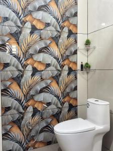 a bathroom with a toilet and a wall mural at VGK Residency in Wayanad