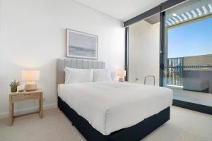 une chambre avec un grand lit blanc et un balcon dans l'établissement Modern Studio with Rooftop and BBQ Access, à North Fremantle