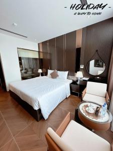 a hotel room with a bed and a tv and chairs at Holiday Hotel Van Don in Tài Xá