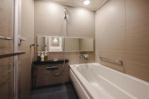 a bathroom with a bath tub and a sink at Hotel Gracery Shinjuku in Tokyo