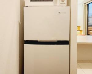 einen weißen Kühlschrank mit einer Mikrowelle darüber in der Unterkunft ZUMI TERRACE うちなーみやリゾート宮古島 in Miyako-jima