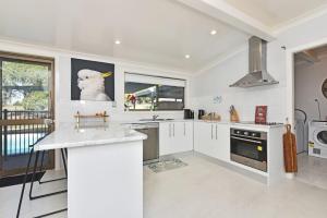 une cuisine avec des armoires blanches et une photo de chien sur le mur dans l'établissement Blaxlands Kangaroo Homestead with Hot Tub walk to Concerts and Wineries, à Pokolbin