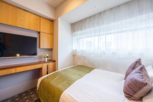 a bedroom with a bed and a flat screen tv at Hotel Gracery Shinjuku in Tokyo