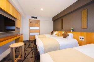 a hotel room with four beds and a flat screen tv at Hotel Gracery Shinjuku in Tokyo