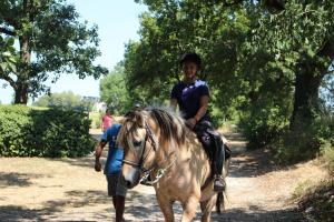 a young girl riding on a horse with a man at Le Vignal in Monflanquin