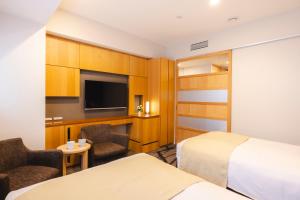 a hotel room with two beds and a flat screen tv at Hotel Gracery Shinjuku in Tokyo