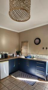 a kitchen with blue cabinets and a clock on the wall at Kuruman Garden Cottages unit 2 in Kuruman