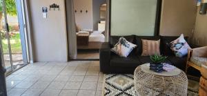a living room with a black couch and a table at Kuruman Garden Cottages unit 2 in Kuruman