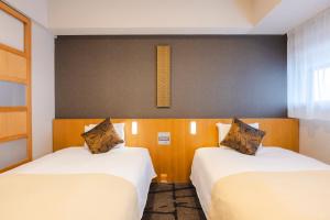 two beds in a hotel room with white sheets at Hotel Gracery Shinjuku in Tokyo