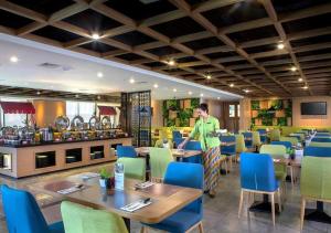 a man standing in a restaurant with tables and chairs at Hotel Dafam Pacific Caesar in Surabaya