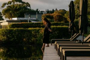 a woman walking down a boardwalk next to a pool at Jackalope Hotel in Merricks North