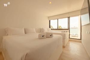 Habitación blanca con 2 camas y ventana grande. en Amazing 4BR Villa with Ocean View in Castillogrande, en Cartagena de Indias