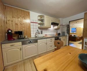 eine Küche mit weißen Schränken und einem Holztisch in der Unterkunft Spirkenhütte Fichtelberg - Ferienhaus bis 6 Personen - mit Sauna - am Fichtelsee in Fichtelberg + 15 Fotos