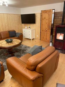 ein Wohnzimmer mit einer Ledercouch und einem Tisch in der Unterkunft Spirkenhütte Fichtelberg - Ferienhaus bis 6 Personen - mit Sauna - am Fichtelsee in Fichtelberg
