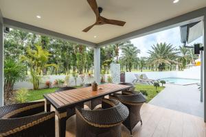 een patio met een houten tafel en stoelen bij V192 Brand New Golf side 5BR Villa with Private Pool in Ban Kathu (1)