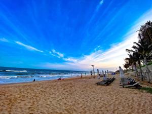 Una playa con sillas y palmeras y el océano. en Nguyên Vũ Apec Mũi Né Mandala, en Ấp Thiẹn Ái