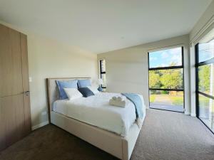 a bedroom with a large bed and a large window at Brand-New Luxury 5 bedroom house in Epsom in Auckland