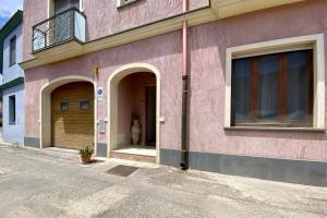a pink building with two doors and a balcony at Civico 21 in Càbras