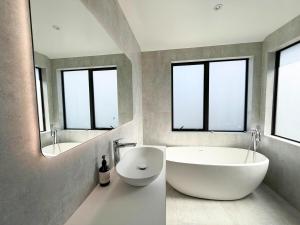 a bathroom with a large white tub and a mirror at Brand-New Luxury 5 bedroom house in Epsom in Auckland +34 photos
