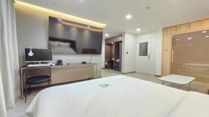 a hotel room with a white bed and a desk at Road35 Hotel in Anseong