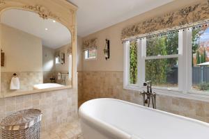 ein Badezimmer mit Badewanne und Waschbecken und einem Fenster in der Unterkunft Collins Cottage - Luxury Accommodation in Bright + 10 Fotos