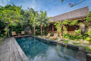 a swimming pool in front of a house at Kubu Kayu Villas in Seminyak