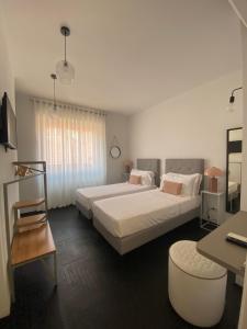 Un dormitorio con dos camas y una mesa y un escritorio. en Loraia Design Rooms, en Porto Ercole