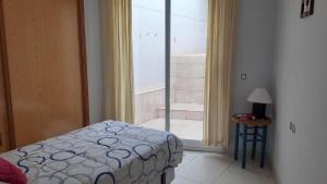 Un dormitorio con una cama al lado de una ventana. en Superbe appartement, en Peñíscola