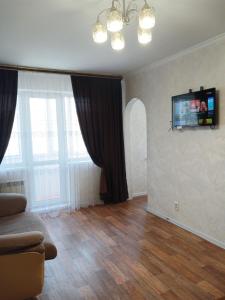 a living room with a couch and a television on the wall at Апартаменты в центре города со смарт тв и Wi-Fi in Karagandy