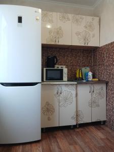 a kitchen with a refrigerator and a microwave at Апартаменты в центре города со смарт тв и Wi-Fi in Karagandy