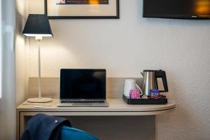 a desk with a laptop and a lamp on it at Best Western Hôtel Royan Océan in Royan