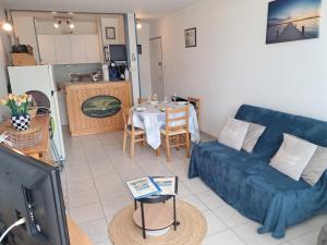 a living room with a blue couch and a table at Aux Mouettes les pieds dans l'eau accès direct à la place 5 personnes in Saint-Hilaire-de-Riez