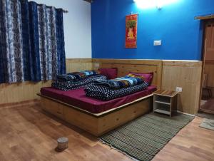 three beds in a room with a blue wall at FE Homestay Kaza By Soma Stays in Kaza
