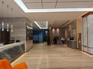 an office lobby with a long hallway with people sitting at desks at 万信至格酒店乌鲁木齐机场德港万达店 in Ürümqi