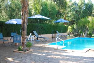 a swimming pool with umbrellas and chairs and a table and a pool at Zena Holiday Villa in Pissouri