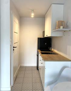 a small kitchen with white cabinets and a black refrigerator at SeaSide in Gdańsk